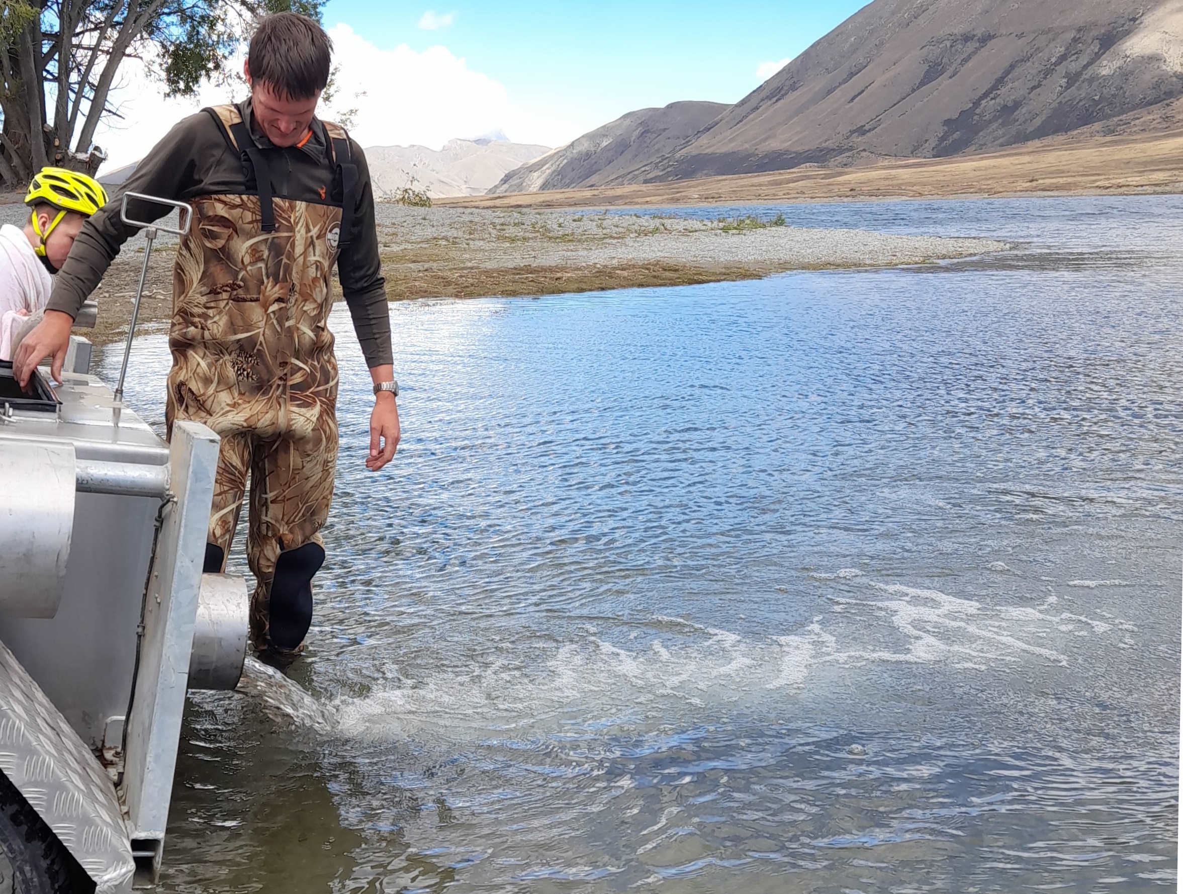 WFR2022.47 Carter Henwood watching on as CSI Fish Game Officer Hamish Stevens releases 7000 rainbow trout into Lake Camp Photo by Sam Coskerie.